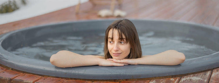 A lady immerses himself in the ice water for cold therapy.