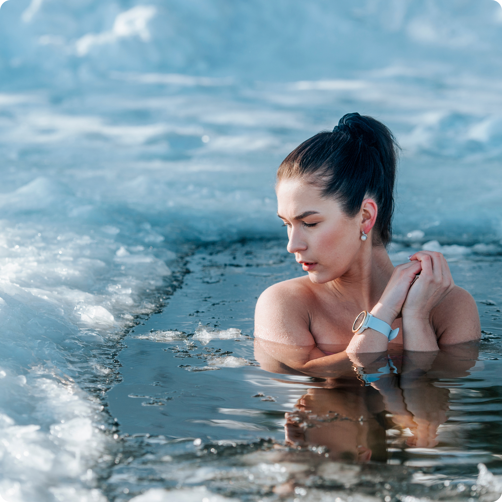 A lady immerses himself in the ice water for cold therapy.